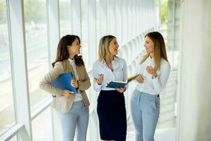 tre ung företag kvinnor har en diskussion medan gående i de kontor hall foto