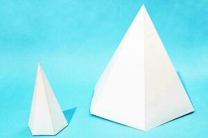 två olika handgjord papper pyramider på blå foto