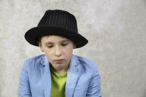 ledsen pojke i en kostym och svart hatt. foto
