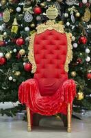 röd stol av santa claus förbi de jul träd. foto