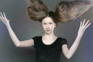 porträtt av en skön Tonårs flicka med fladdrande strängar av hår. foto