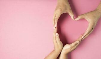 vuxen händer tillverkad hjärta symbol på rosa bakgrund , hälsa vård, organ donation, familj liv försäkring, värld hjärta dag, värld hälsa dag, bön- begrepp foto