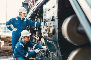 tåg ingenjör team arbetssätt service underhåll gammal smutsig årgång klassisk ånga motor lokomotiv i tåg reparera verkstad på tåg station. foto