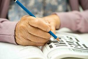 alzheimers sjukdom annons, asiatisk äldre kvinna spelar sudoku pussel spel till öva hjärna Träning för demens förebyggande. foto