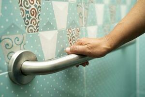 asiatisk äldre kvinna använda sig av badrum hantera säkerhet i toalett, friska stark medicinsk begrepp. foto