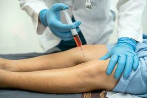 asiatisk läkare injicera hyaluronsyra blodplättsrik plasma i knät på äldre kvinna för att gå utan smärta. foto