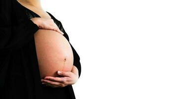 gravid kvinna bär svart klänning och innehar händer på svullen mage isolerat på vit bakgrund och kopia Plats med klippning väg. graviditet 7-9 månader, moderskap, kärlek, förväntan och vård bebis. foto