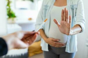 rökning och graviditet. gravid flicka vägrar till ta cigarett gestikulerar sluta. gravid kvinna med mage vägrar passiv rökning. de begrepp av de avslag av dålig vanor foto