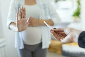 rökning och graviditet. gravid flicka vägrar till ta cigarett gestikulerar sluta. gravid kvinna med mage vägrar passiv rökning. de begrepp av de avslag av dålig vanor foto
