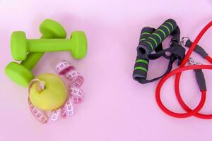 en grön äpple, och en centimeter mätning tejp på en rosa bakgrund. sporter, sporter näring, friska äter, diet. Plats för de text. foto