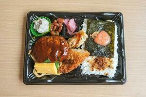 japansk bento uppsättning lunch låda av hamburgare biff, tång på ris, friterad fisk och japansk rullad omelett foto