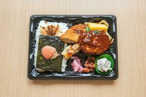 japansk bento uppsättning lunch låda av hamburgare biff, tång på ris, friterad fisk och japansk rullad omelett foto