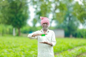 indisk Lycklig jordbrukare innehav tömma flaska i händer, Lycklig jordbrukare som visar vit flaska foto