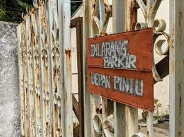 varning tecken med skrivning i indonesiska Nej parkering i främre av dörr foto