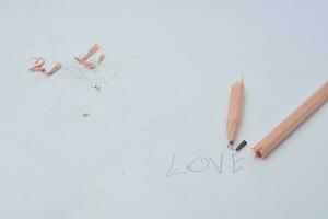 bruten penna. skrivning med en penna de ord kärlek. vit bakgrund. foto