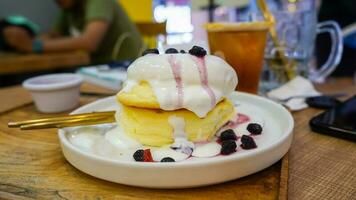 hemlagad fluffig japansk pannkakor med bär sås och is grädde garnering på en vit tallrik foto