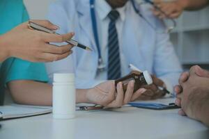 medicinsk team har en möte med doktorer i vit labb rockar och kirurgisk scrubs sittande på en tabell diskuterar en patienter rekord, framgång medicinsk hälsa vård, medicin läkares arbetssätt begrepp foto