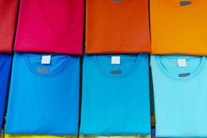 närbild av färgglada t-shirts på galgar