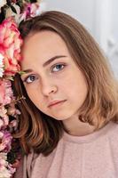 porträtt av en ung flicka vid väggen med blommor. foto