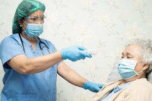 asiatisk läkare som bär ansiktsskydd och folkdräkt nytt normalt för att kontrollera patientens skydd infektion covid-19 koronavirusutbrott vid karantän vårdavdelningen. foto