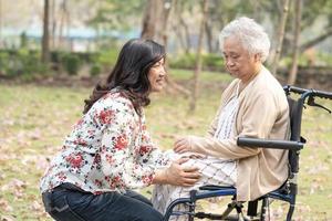 asiatisk senior eller äldre gammal damkvinnapatient med omsorg, hjälp och stöd glad på rullstol i park i semestern, hälsosamt starkt medicinskt koncept. foto