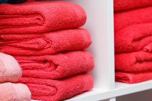 några röda handdukar på vit hylla, spasalong, butik, badrumstextil. foto