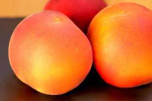 mogen persikafrukt, tre persikor prunus persica på nära håll på svart bakgrund foto