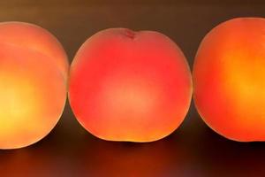 mogen persikafrukt, tre persikor prunus persica på nära håll på svart bakgrund foto