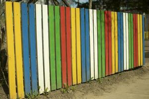 glad staket tillverkad av färgad brädor. staket i parkera. kreativ design lösning. foto