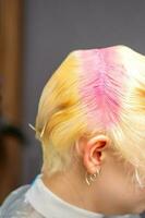 ung caucasian kvinna nyanser hår rötter i rosa Färg i en skönhet salong. foto