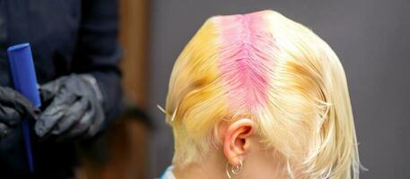 ung caucasian kvinna nyanser hår rötter i rosa Färg i en skönhet salong. foto