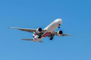 uae baserad luft företag emirates med flygplan boeing 777-300er närmar sig till landa på lissabon internationell flygplats mot blå himmel foto