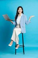asiatisk affärskvinna porträtt Sammanträde på stol, isolerat på blå bakgrund foto