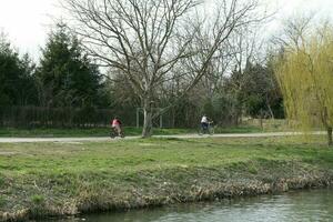 eftermiddag fortfarande liv i szeged. barn ridning de cykel på de maros kust foto