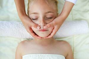 massör håller på med ansikte massage till barn. foto