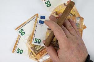 Räkningar på 50 euro med mans cigarrhand foto