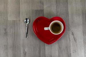 en kopp kaffe med ett hjärtformat fat foto