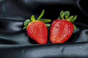 mogna jordgubbar på svart satängtygbakgrund foto