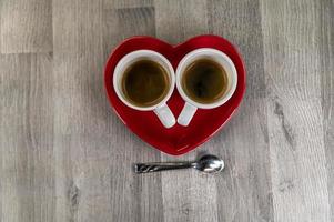 två små koppar kaffe med en hjärtfat foto