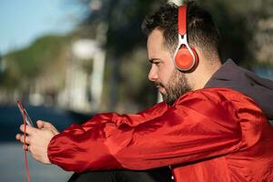 ung man i sportkläder lyssnande till musik med en par av hörlurar foto