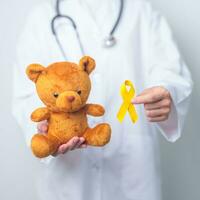 internationell barndom cancer medvetenhet månad, läkare med barn leksak och gyllene Färg band för stödjande barn levande. sjukvård och värld cancer dag begrepp foto