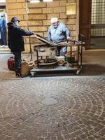 man som säljer kokta kastanjer till allmänheten i stadens centrum foto