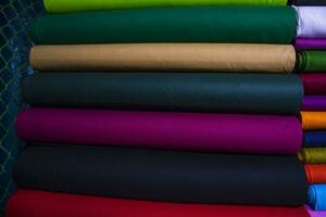 konstnärlig mängd skugga tona färger textil- tyger staplade på detaljhandeln affär hylla till försäljning foto
