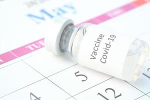 vaccindagskonceptglasampull med vaccin och spruta i kalendern