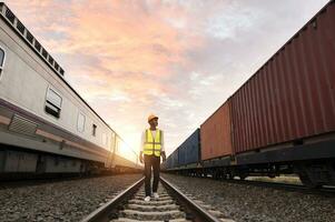 ingenjör inspekterar behållare tåg av transport företag distribution och transport av varor förbi järnväg en behållare tåg godkänd genom ett industriell område foto