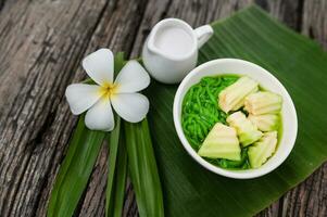 lod chong doftande pandan ris droppande in i kokos mjölk i en trä- skål på en grön banan blad bakgrund. eller lod chong blandad med thai meloner asiatisk thai desserter foto