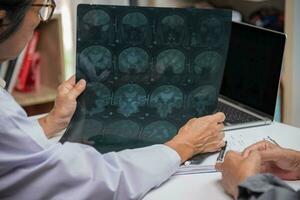 asiatisk kvinna läkare tittar på patient röntgen filma, mri och ct skanna. hälsa vård begrepp. foto