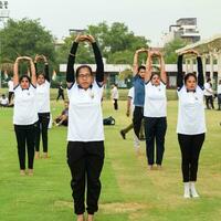 ny delhi, Indien, juni 21, 2023 - grupp yoga övning session för människor på yamuna sporter komplex i delhi på internationell yoga dag, stor grupp av vuxna delta yoga klass i cricket stadion foto