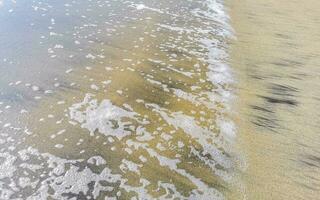 våt strand sand vatten och vågor textur och mönster i Mexiko. foto