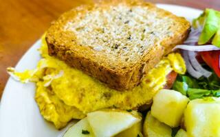 rostat bröd med krypterade ägg sallad lök avokado tomater potatisar Mexiko. foto